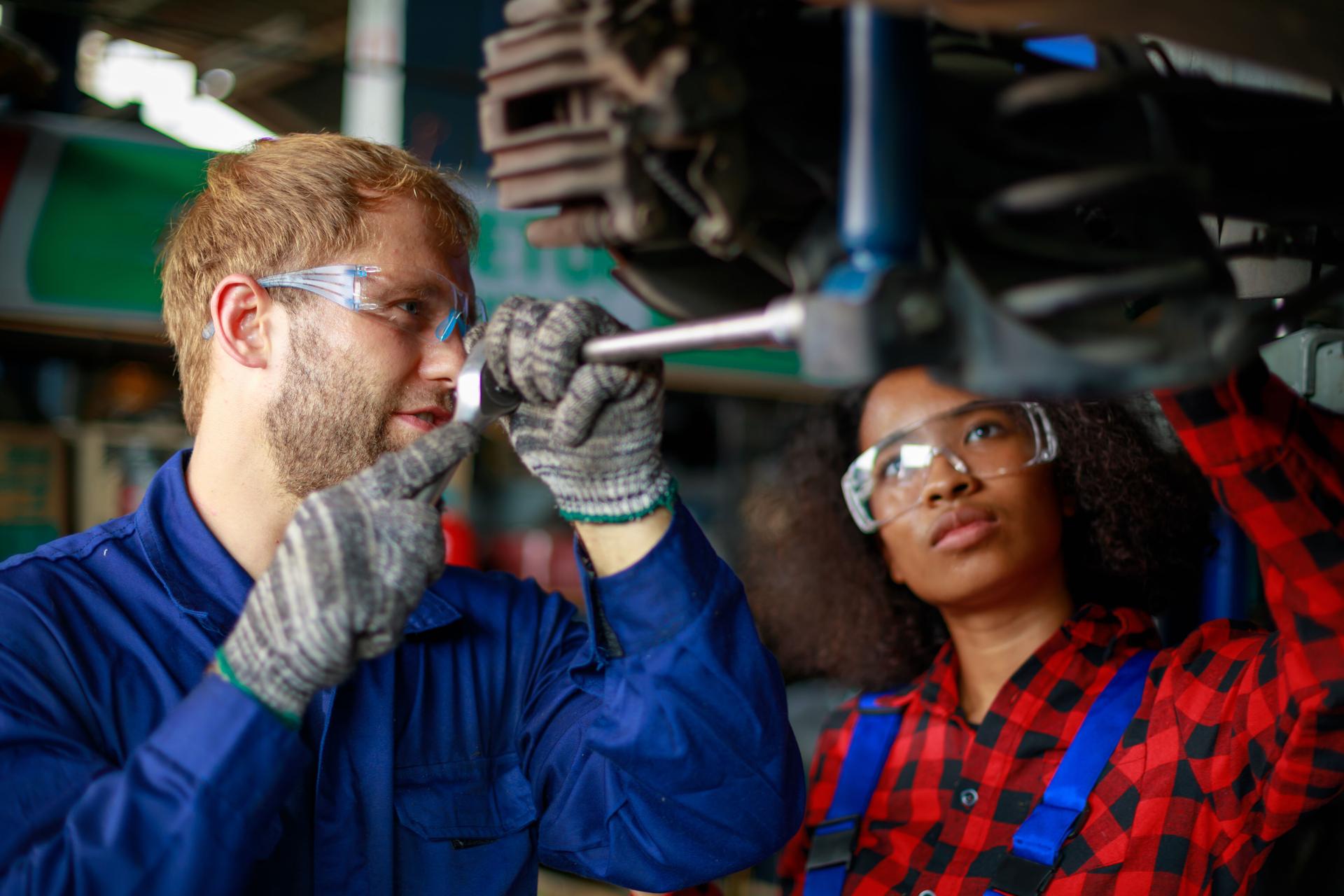 Two mechanics at work. Two confident auto mechanic working at the repair shop.