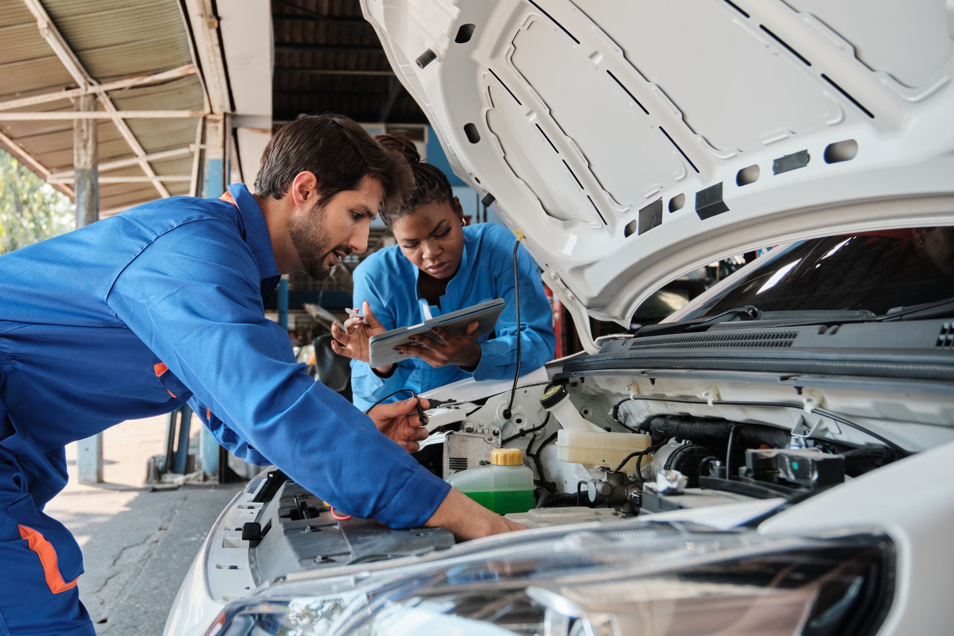 The mechanic's coworkers check the EV car in the service garage.